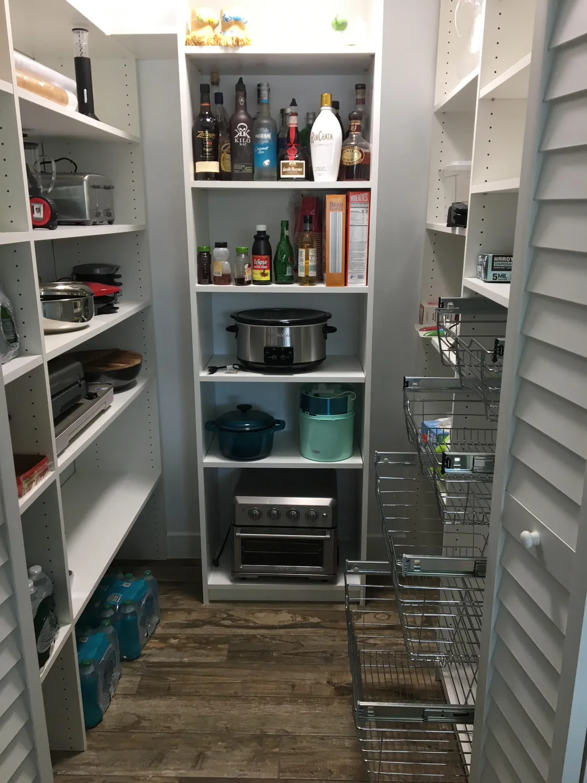 Custom walk-in pantry with fully stocked white shelving, drawers, and small-appliance storage