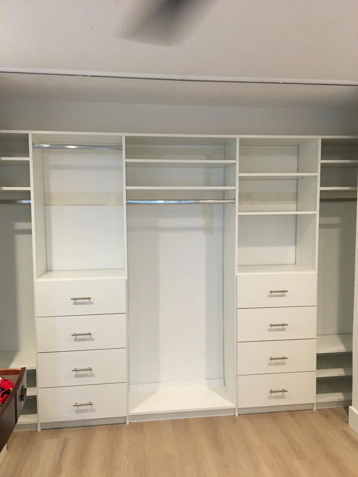 Finished custom walk-in closet with white shelving, drawers, and hanging sections