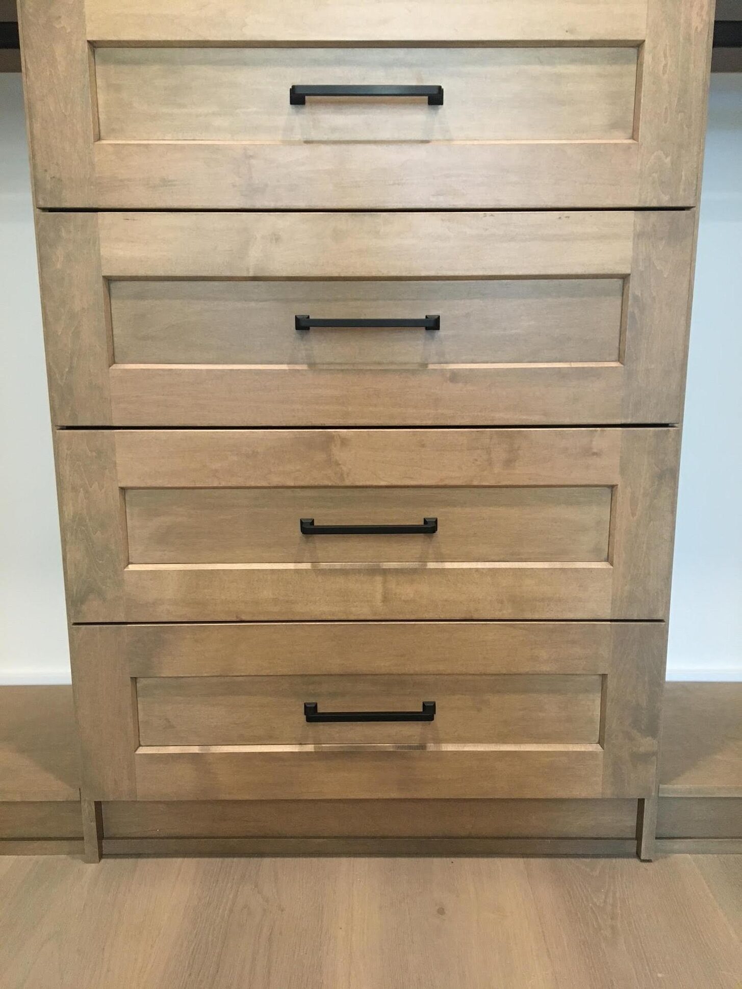 Detail of warm wood custom closet drawer fronts with matte-black bar pulls